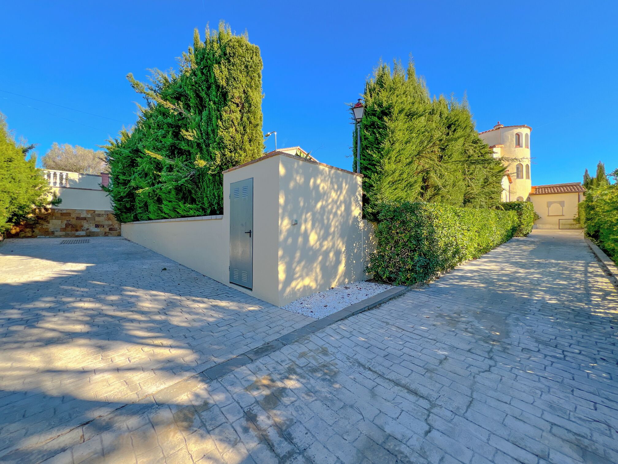 Un chemin pavé bordé de verdure et un bâtiment doté d’un toit en tuiles.