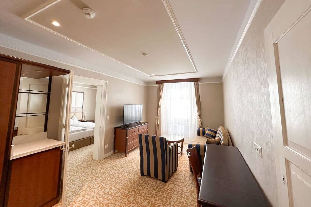 Ein Hotelzimmer mit Bett, Fernseher, Schreibtisch, Stuhl und Kleiderschrank.