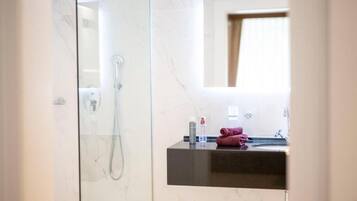 A modern bathroom with a glass-enclosed shower, a dark countertop sink, and a mirror above it.