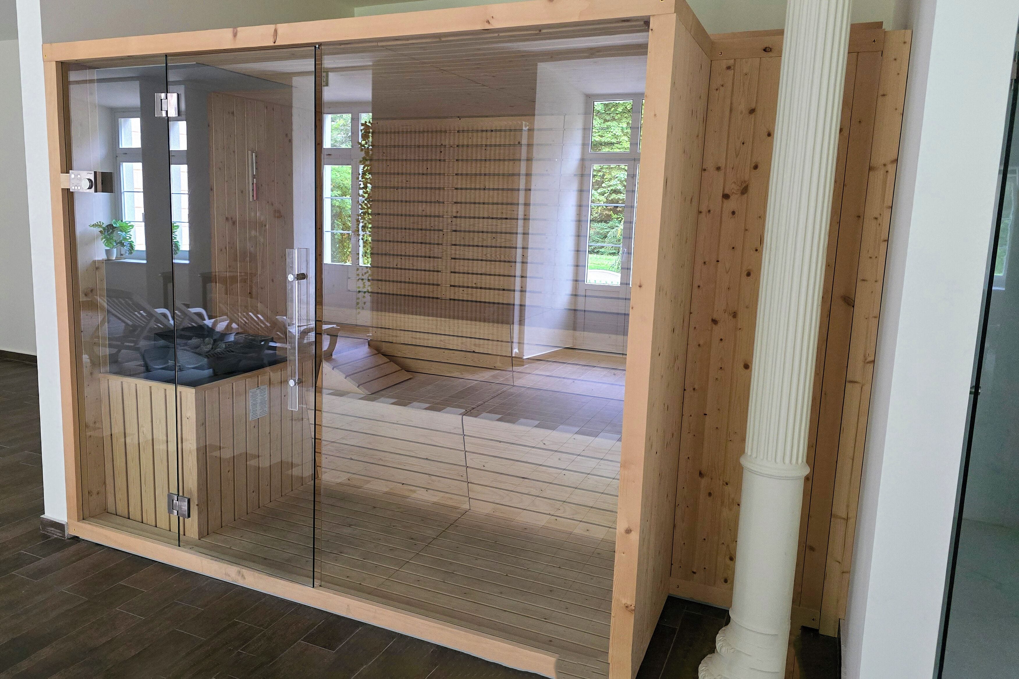 A room with a sliding glass door, wooden flooring, and a view of greenery outside.
