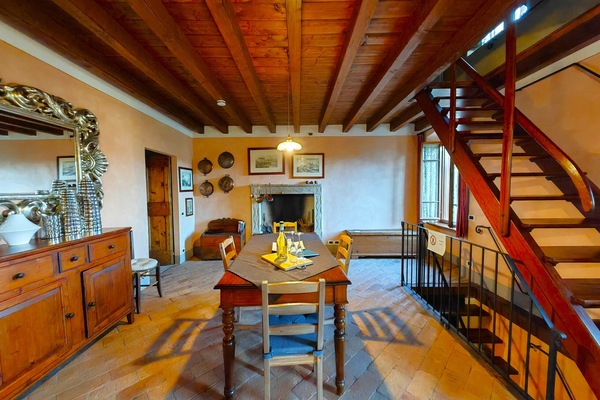 Charmanter Speisesaal im rustikalen Stil mit sichtbaren Balken und Kamin, ideal für gesellige Momente in der Ferienwohnung in Monzambano.