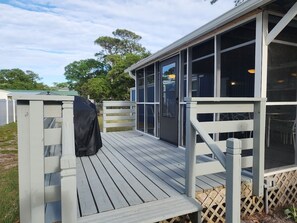 Eine überdachte Terrasse mit Grill, eine einsehbare Veranda und Blick auf die Umgebung.