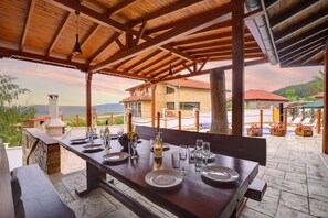 A covered outdoor dining area with a table set for six, overlooking a scenic landscape. - Guest house Andrea (Dobrich Province)