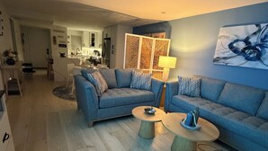 A modern living room with two sofas, a coffee table, and a kitchen in the background.