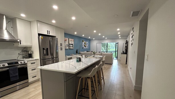 A modern kitchen with a central island, stainless steel appliances, and a dining area with bar stools.