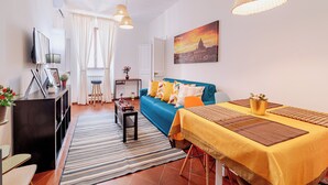 En moderne stue med sofa, spisebord og fjernsyn.