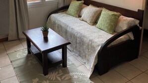 Une chambre à coucher avec un lit, une table de chevet ornée d’une plante, une fenêtre avec des rideaux et deux appliques murales.