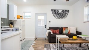 A compact living space with a kitchenette, a sofa, a coffee table, and a patterned rug. - Mockingbird Bungalow min to beaches (Gulfport)