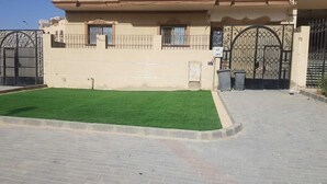 A building with a paved entrance area and a green lawn. - 2-bedroom apartment in terrific New Cairo with WiFi (Industrial Area)