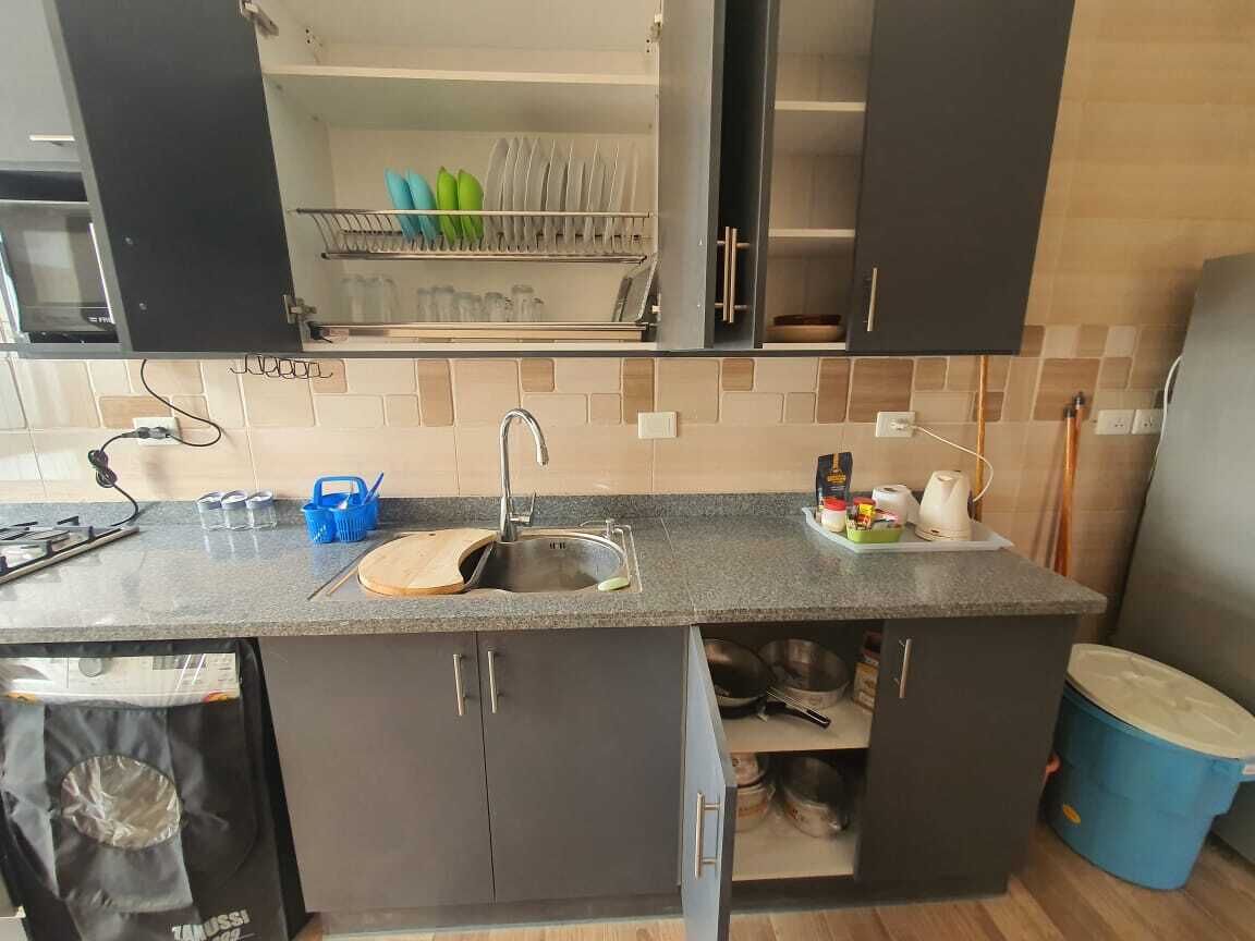 Une cuisine de taille réduite, équipée d’un évier, d’un plan de travail et de placards.