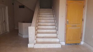A staircase leading to a door, with a concrete structure on the left and a plain wall on the right. - 2-bedroom apartment in terrific New Cairo with WiFi (Industrial Area)
