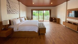 Un dormitorio amplio con una cama grande, un televisor y un ventanal corredera que da a un balcón.