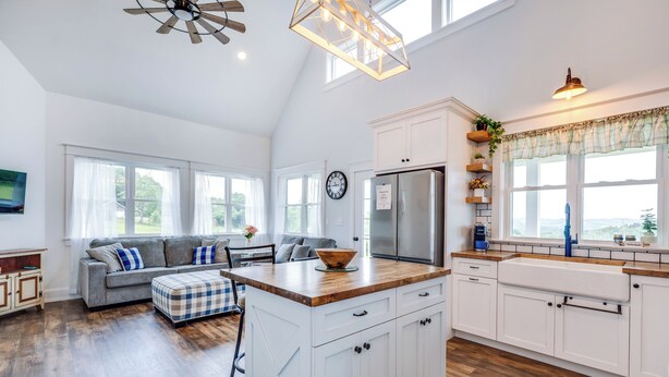 A spacious kitchen with white cabinetry, a wooden countertop, and a built-in island. There is a large window providing natural light and a view of the outdoors. - Azur Hillside Haven: A Perfect Wellsboro Getaway! (Charleston Township)