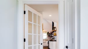 A hallway with a white door leading to a kitchen area. - Azur Hillside Haven: A Perfect Wellsboro Getaway! (Charleston Township)