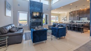 A spacious living area with a fireplace, two sofas, a TV, and a kitchen with bar stools.