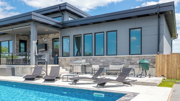 A modern house with a swimming pool, outdoor seating, and a barbecue area.