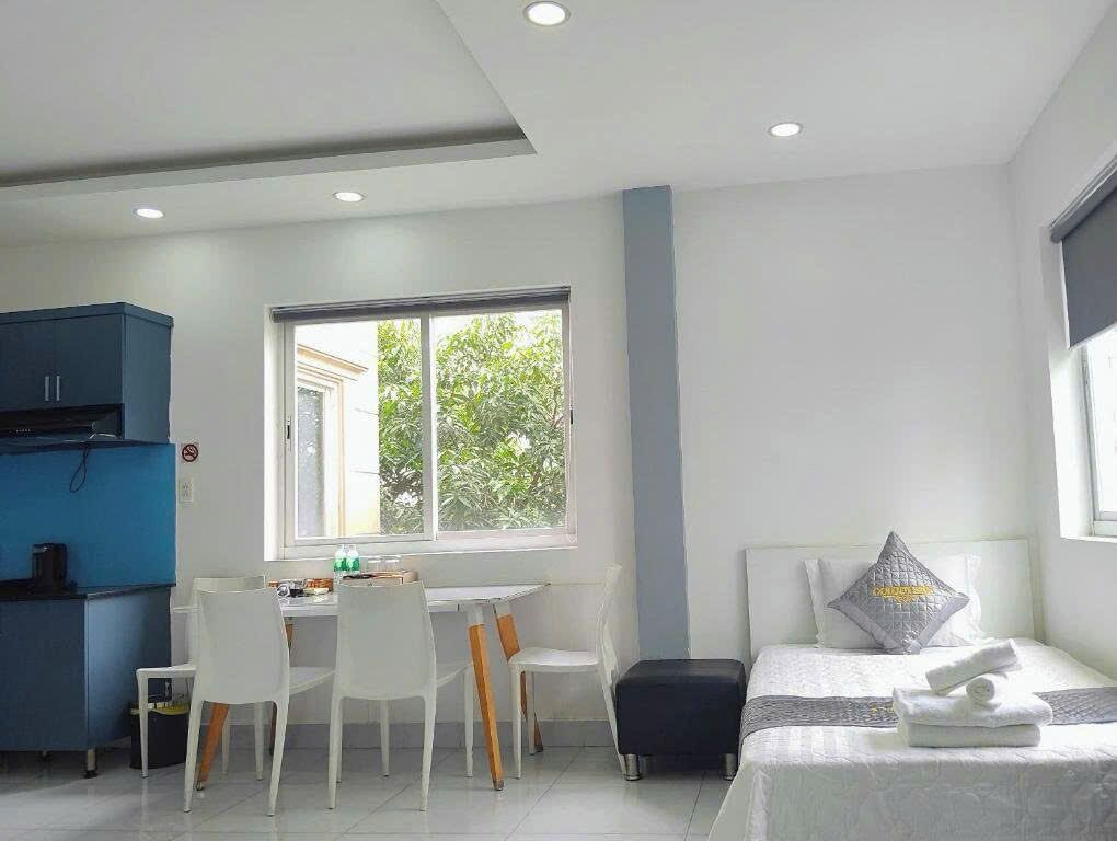 A room with a bed, a desk with chairs, a window, and a blue cabinet.