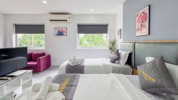 Une chambre d’hôtel moderne équipée de deux lits, d’une télévision, d’un bureau et d’un canapé.
