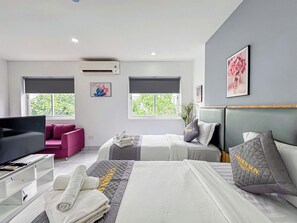 Une chambre d’hôtel moderne équipée de deux lits, d’une télévision, d’un bureau et d’un canapé.