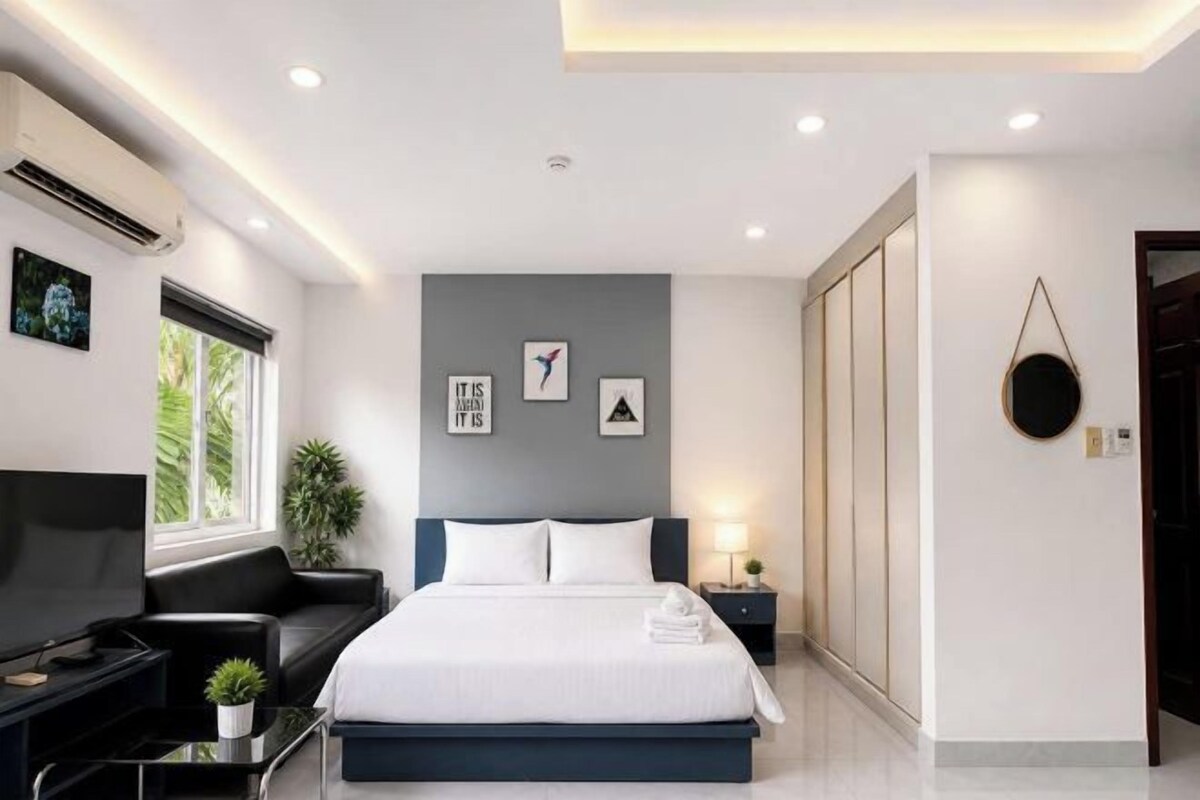 Un dormitorio moderno con cama, televisión, escritorio y ventana.