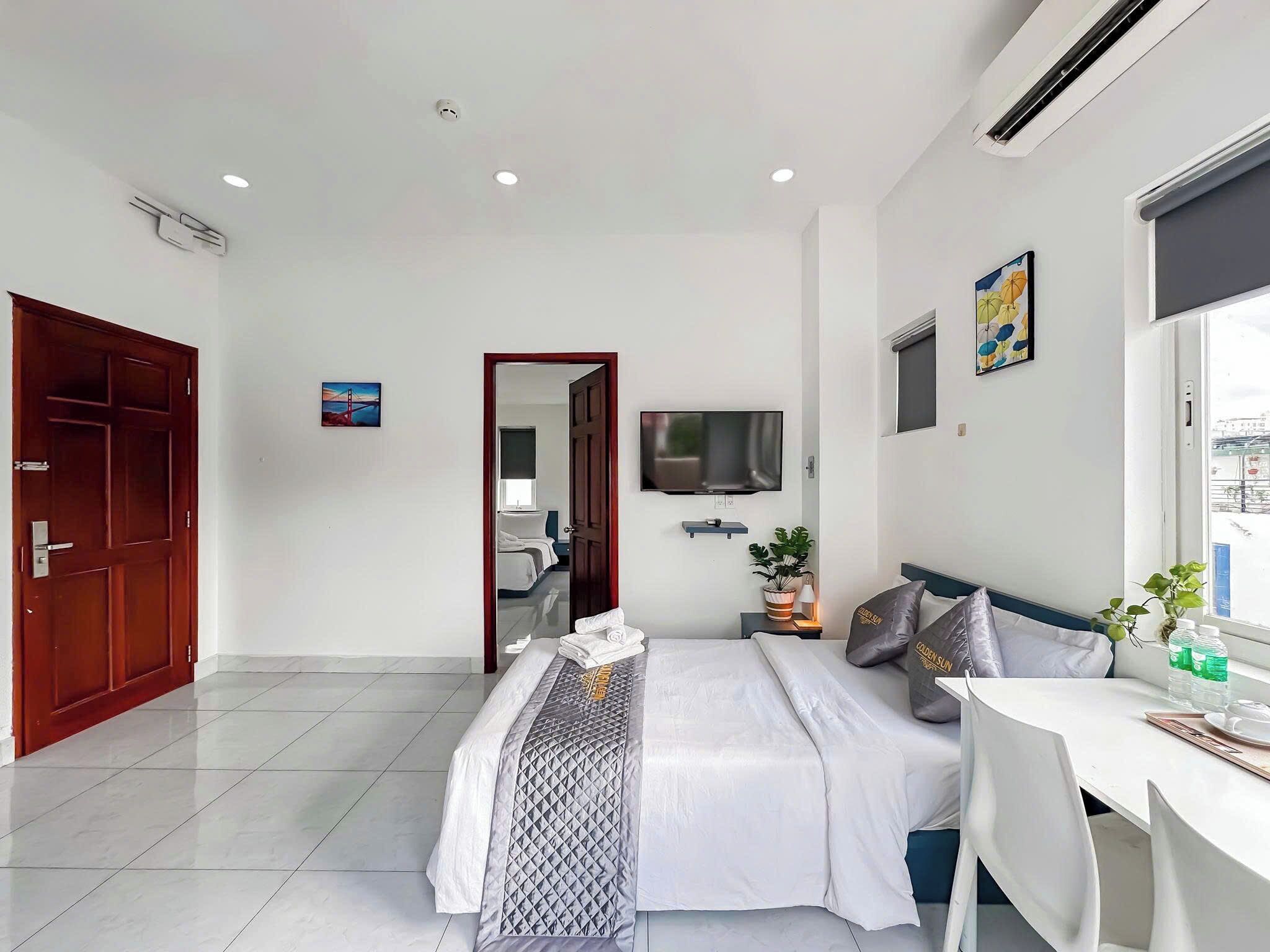 Una habitación de hotel moderna con una cama grande, un televisor montado en la pared, una mesa de comedor y una ventana con vistas a la ciudad.