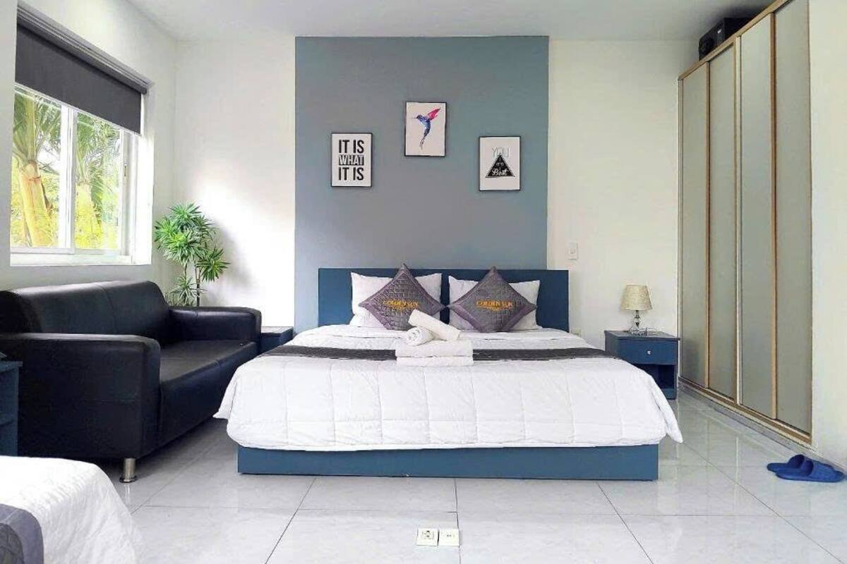 Ein modernes Schlafzimmer mit Bett, Sofa, Nachttisch und Kleiderschrank.