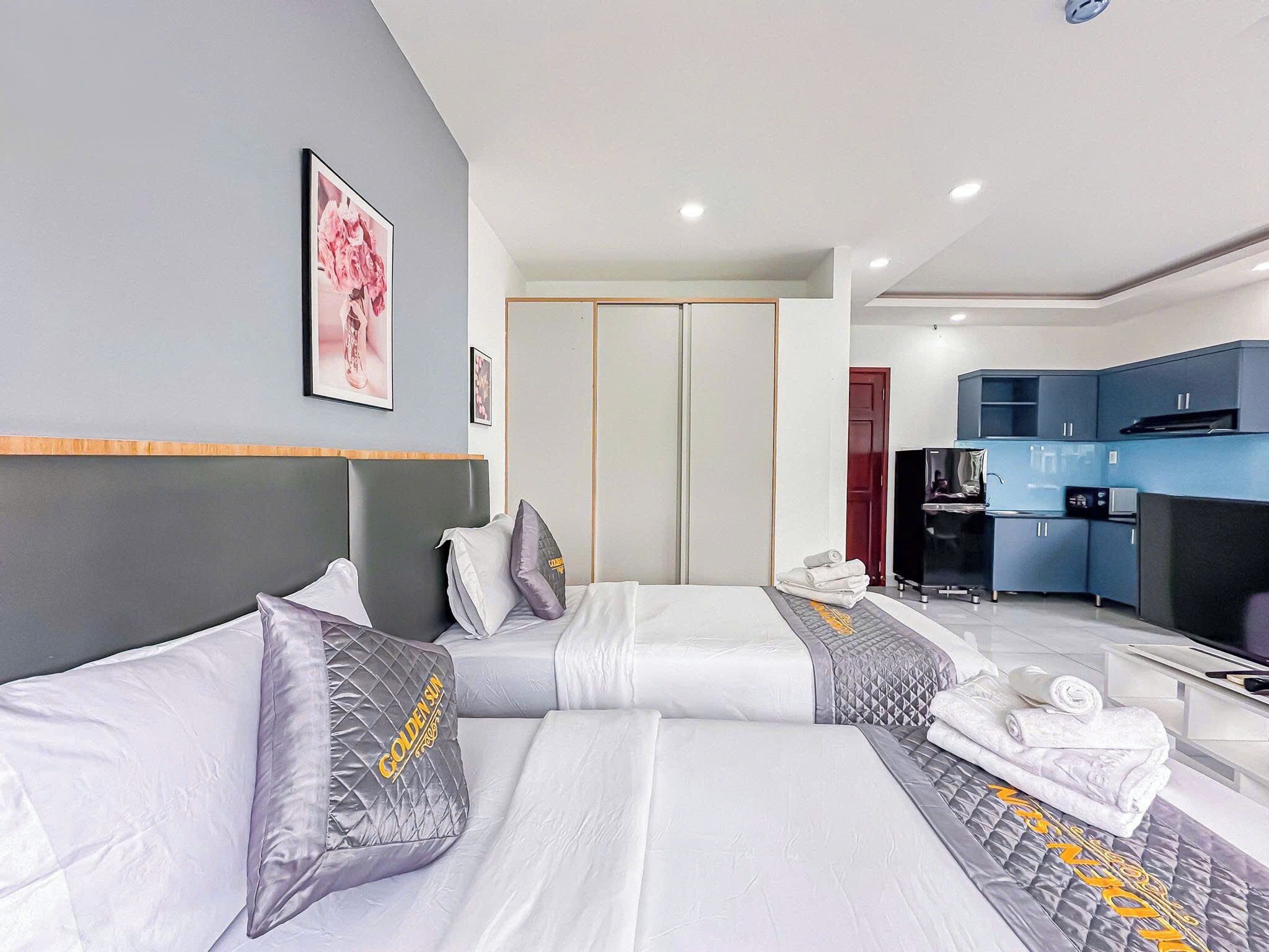 A hotel room with two beds, a kitchenette, and a wardrobe.
