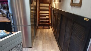 Een smalle keuken met een houten plafond, een roestvrijstalen koelkast en een decoratieve spatwand.