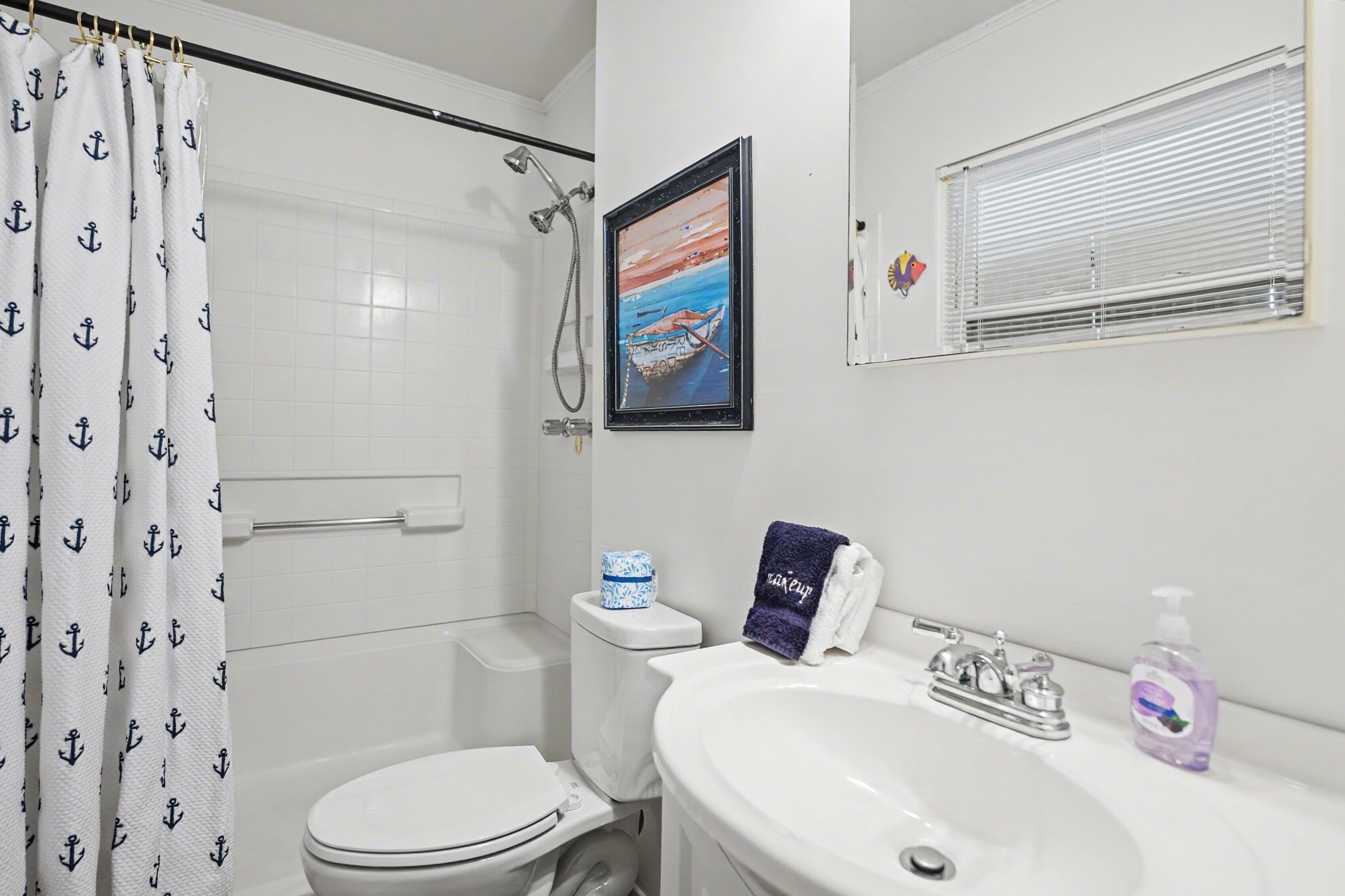Une salle de bain équipée d’une douche, de toilettes, d’un lavabo et d’un tableau encadré au mur.