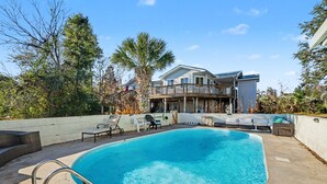 Ein Schwimmbad mit Liegestühlen und einer Terrasse, im Hintergrund ein Haus.