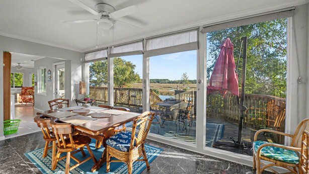 Ein großzügiger Essbereich mit einem großen Tisch und Stühlen, einem Deckenventilator und Blick auf eine Terrasse und einen Außenbereich.