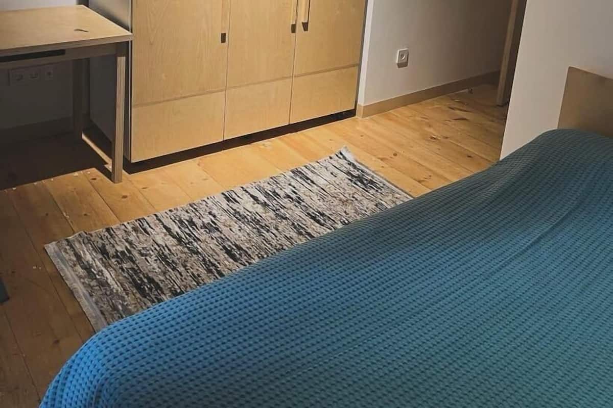 Ein Schlafzimmer mit einem Bett, einem Holzschrank und einem Schreibtisch.