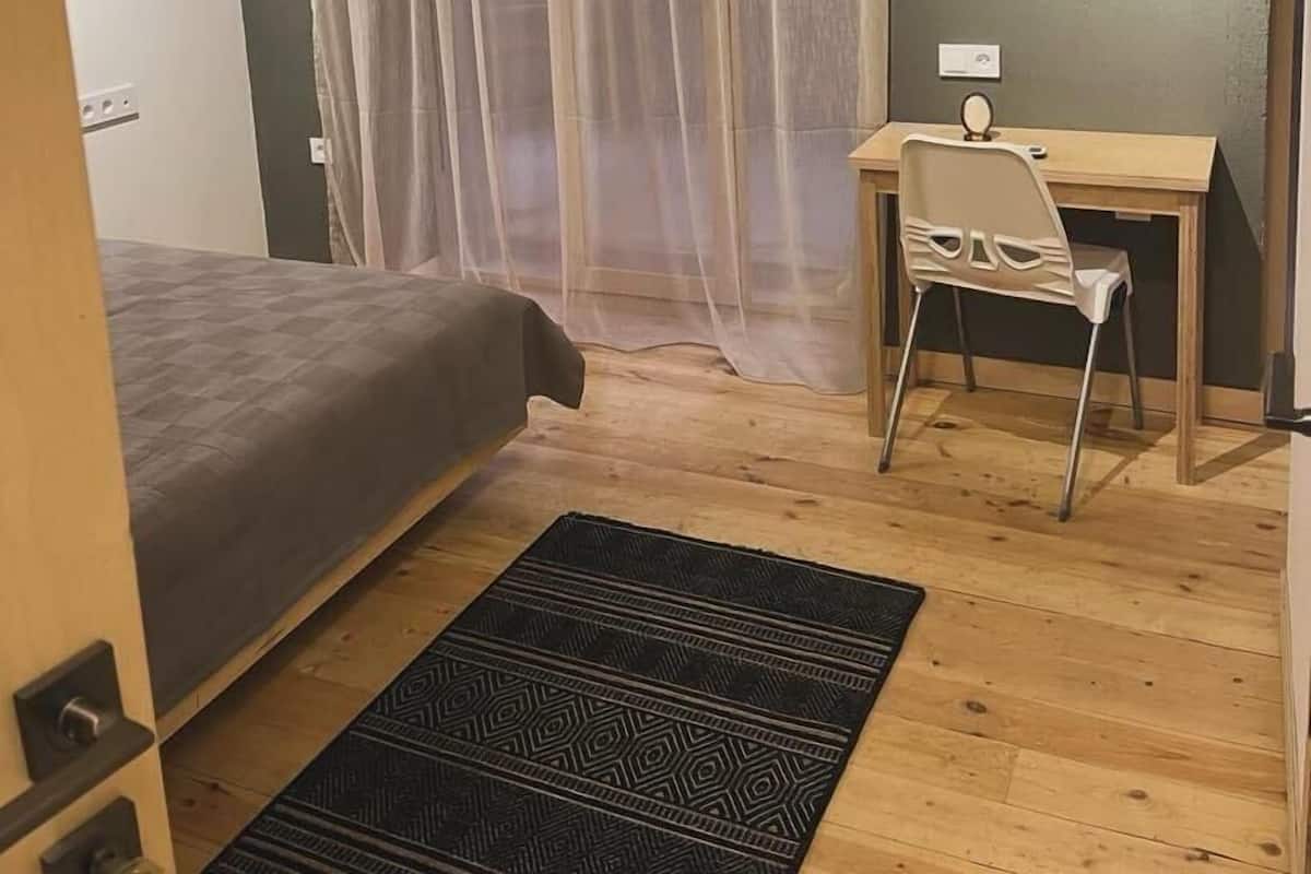 Ein kleiner, gemütlicher Raum mit einem Bett, einem Schreibtisch und einem Stuhl.