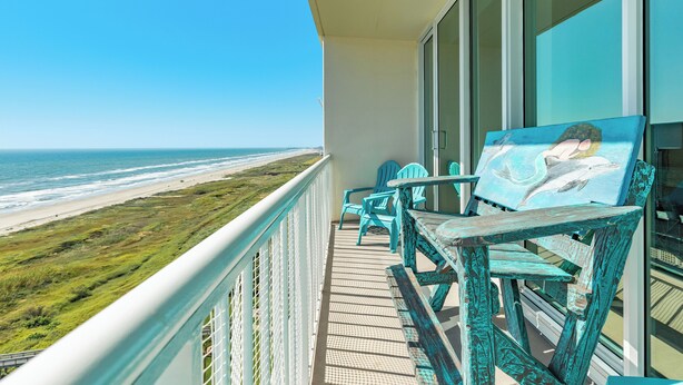 A balcony with a view of the beach, turquoise chairs, and a painting of a dolphin. - 1200 TOP OF EAST BEACH! (Galveston)