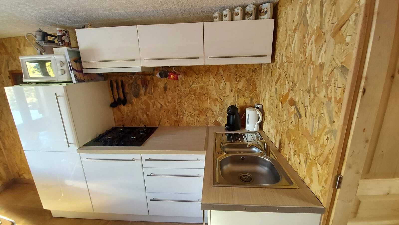 Una cocina compacta con armarios blancos, un lavamanos de acero inoxidable y un microondas.