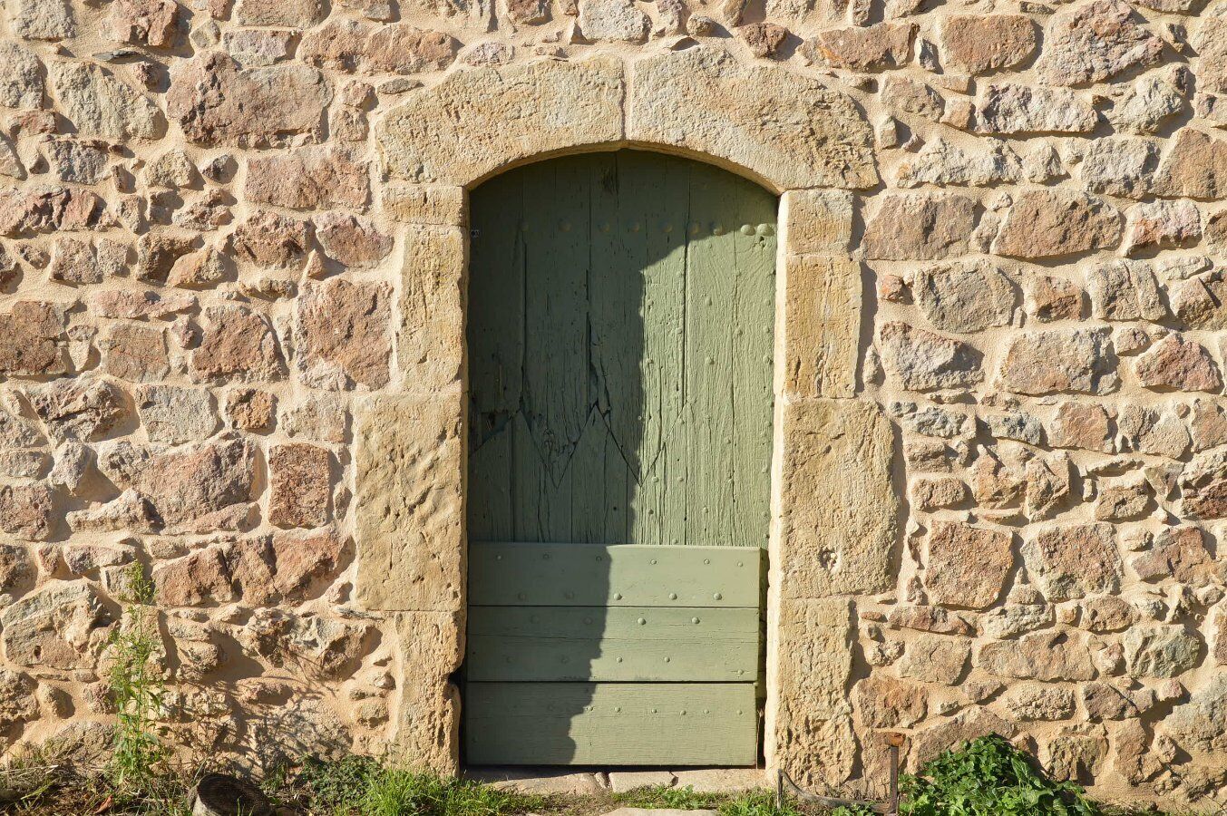Un mur de pierre avec une porte en bois peinte en vert.