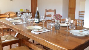 Een eettafel gedekt met borden, wijnglazen en een fles wijn.