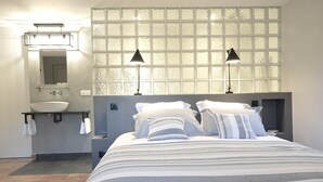 Een hotelkamer met een groot bed, een badkamer met een wastafel en een glasraam met gezandstraalde motieven.