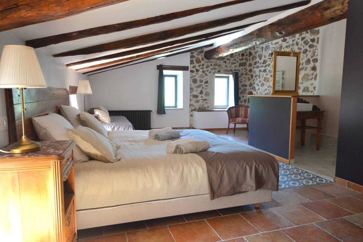 A bedroom with a bed, bedside lamps, a dresser, a chair, and a mirror.