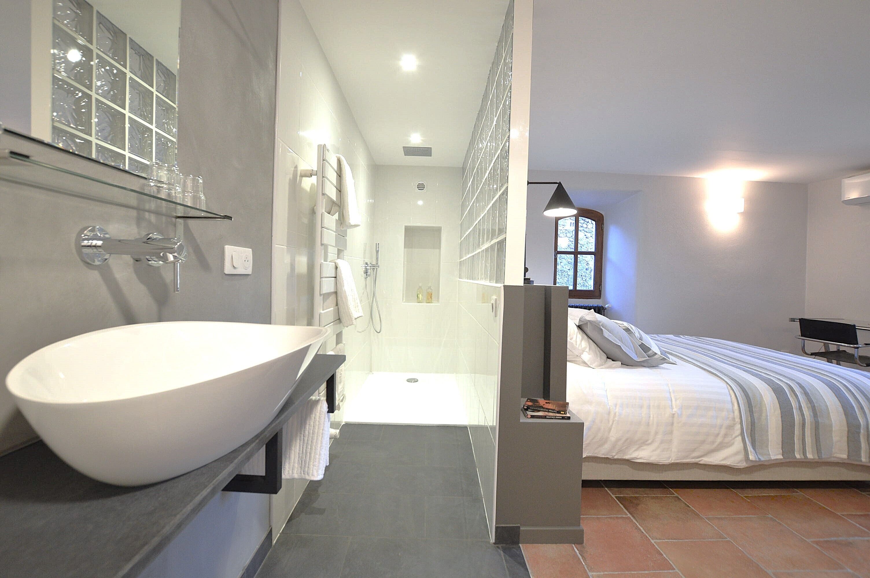 A modern bathroom with a large white sink, a glass shower enclosure, and a separate shower area.