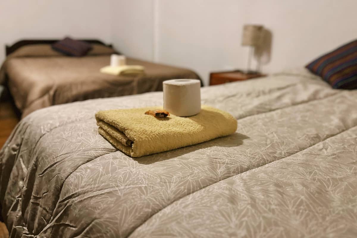 A hotel room with two beds, each with a different textured bedspread.
