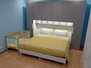 A bedroom with a bed, a crib, and a wardrobe.