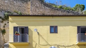 Ein gelbes Gebäude mit zwei Balkonen, einer kleinen Tür und einem Fenster.