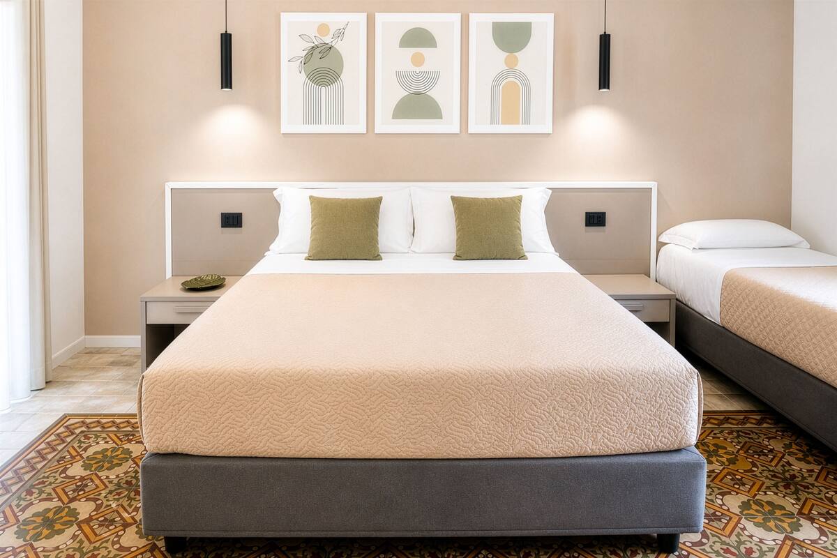 Ein Hotelzimmer mit einem großen Bett, zwei Nachttischen und einem gemusterten Teppich.