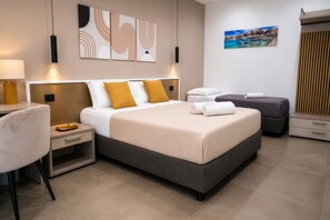A modern hotel room with a large bed, bedside tables, a chair, and artwork on the walls.