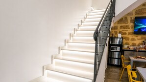 Eine moderne Küche mit Treppe, Steinwand und Flachbildfernseher.