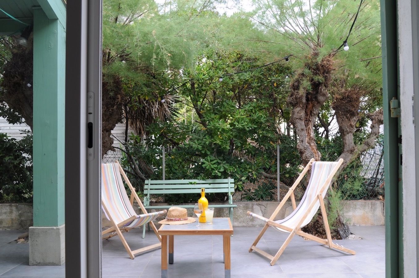 An outdoor seating area with two wooden chairs and a table, a bench, and a hammock.