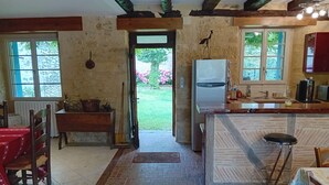 Eine rustikale Küche mit einer Holzbank, einem Kühlschrank und einem Fenster mit Blick auf Grünflächen.