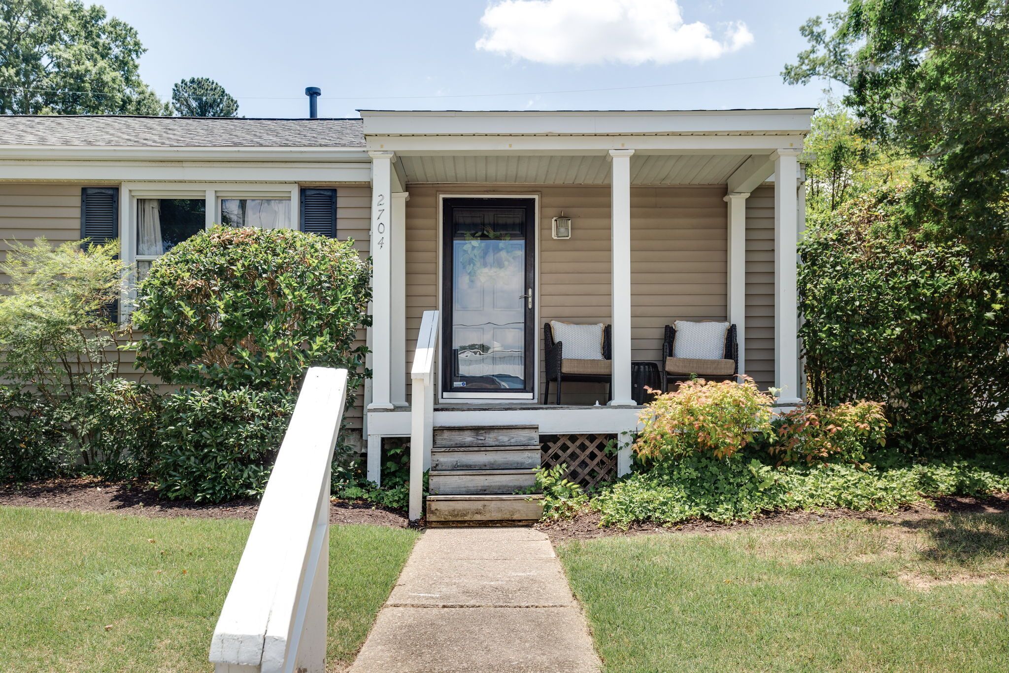 A single-story house with a front porch, a mailbox, and a small garden area.