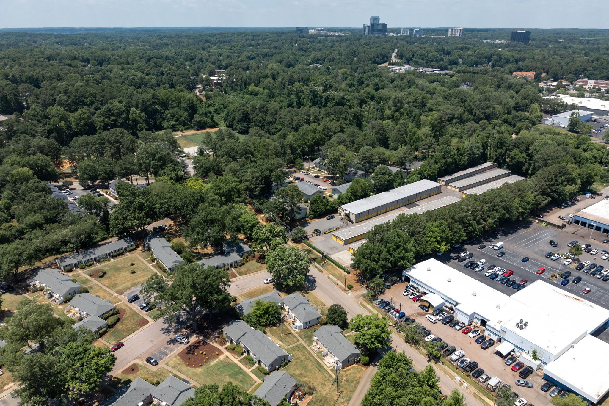 Vista aerea di una zona residenziale con case singole, un grande edificio industriale e un parcheggio.